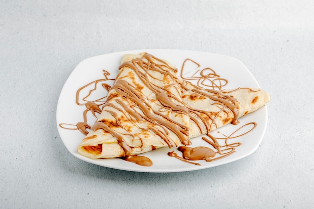 Free Photo crepe with chocolate cocoa syrup in a white plate in a white background.