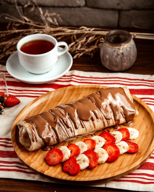 Crepe with fruits  strawberry  banana  chocolate  tea  side view