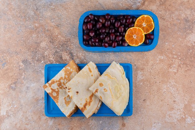 Crepes with orange and cherries in a blue platter