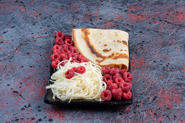 Crepes with white cheese and raspberries in a white plate. 