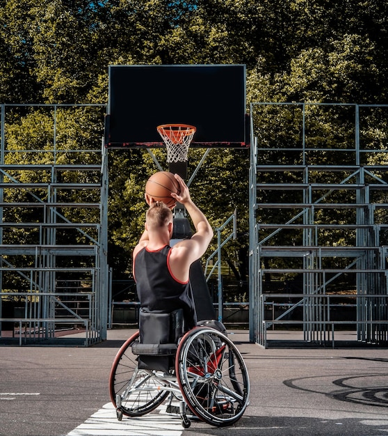 Free Photo cripple basketball player in a wheelchair plays on an open gaming ground.