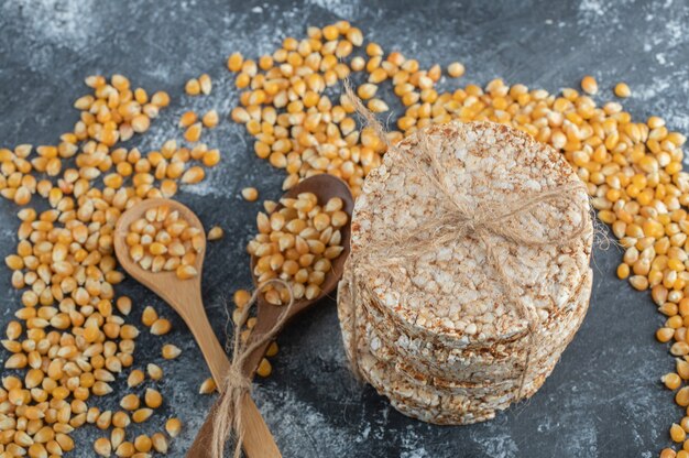 Crisp bread in rope with wooden spoons of uncooked popcorn seeds.