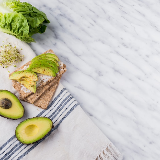 Crisp bread with sliced avocado on marble table