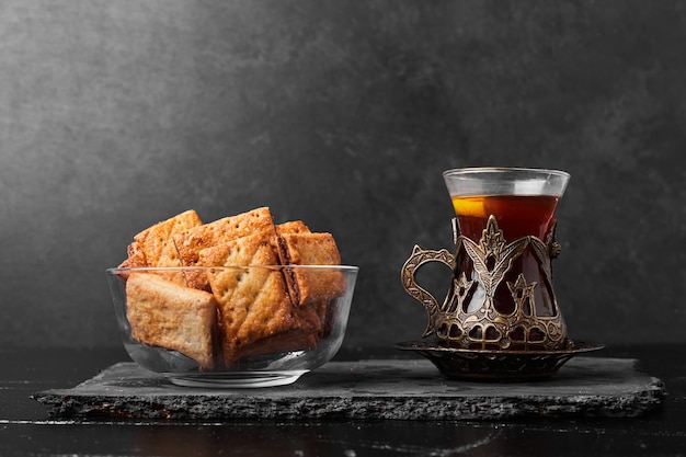 Crispy crackes in a glass cup with a glass of tea on a stone board.