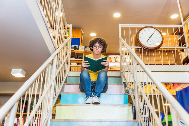 Crispy female reading book sitting on steps. 