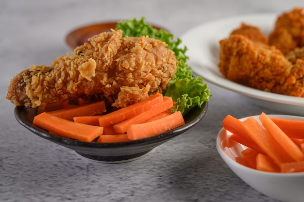 Crispy fried chicken on a plate with salad and carrot