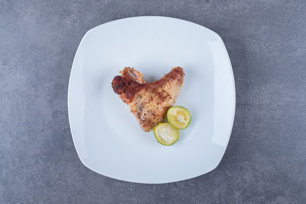 Crispy fried wing on white plate.