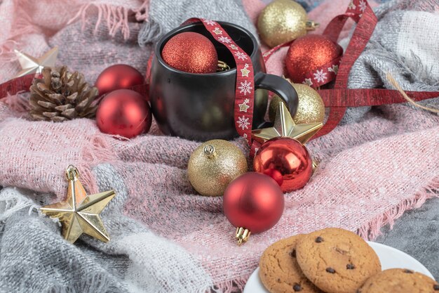 Crispy ginger cookies in a white saucer with a cup of drink and christmas ornaments around