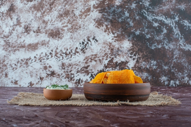 Crispy potato chips and yogurt in a plates on texture, on the marble table. 