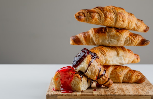 Free photo croissant on a cutting board with jam side view