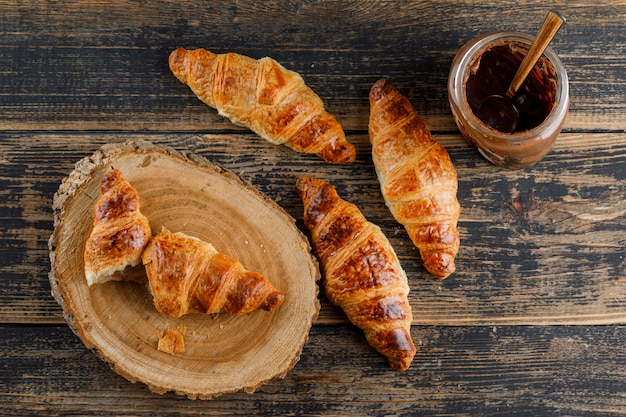 Free photo croissant with chocolate cream flat lay on wooden and cutting board