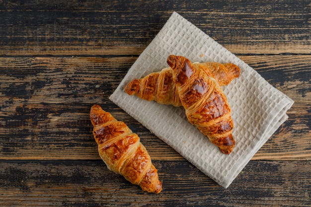 Free photo croissant on wooden and kitchen towel. flat lay.