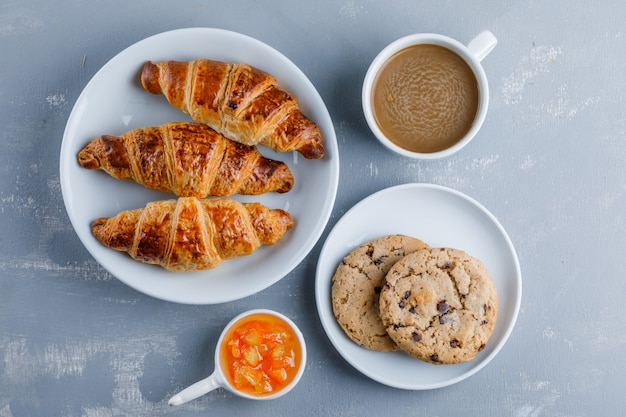 Free photo croissants in a plate with cup of coffee, cookies, jam top view