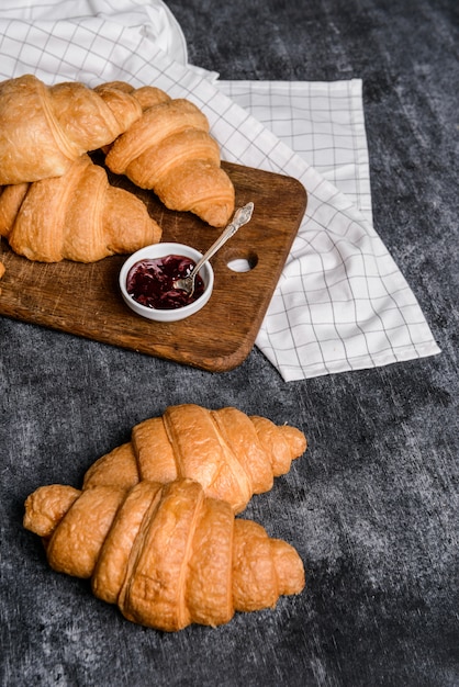  croissants and pot with jam aside on grey table