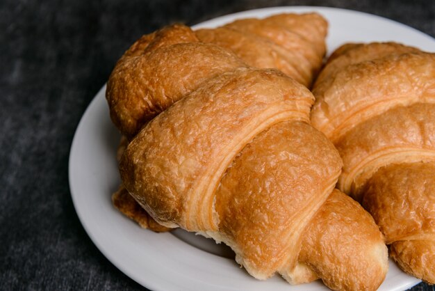  croissants on white round plate and grey table wall.