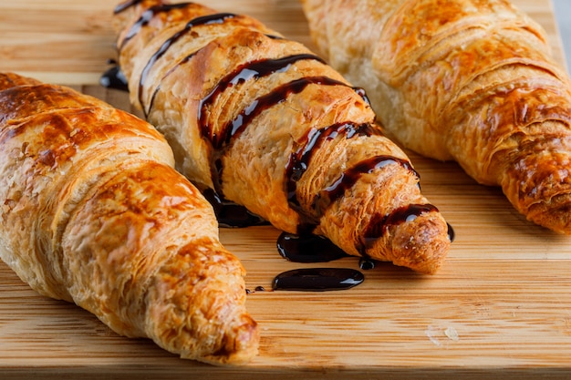 Free photo croissants with chocolate sauce close-up on a wooden table