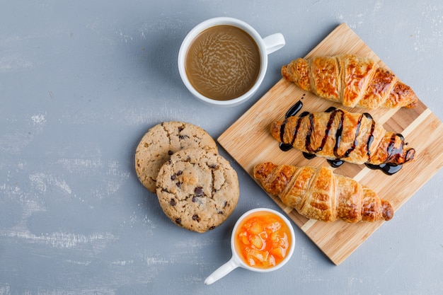 Free photo croissants with coffee, cookies, sauce flat lay on plaster and wooden board