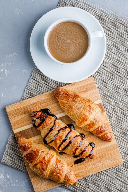 Croissants with coffee, cutting board, flat lay.