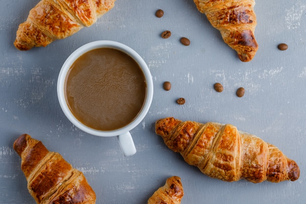 Free photo croissants with cup of coffee, coffee beans, flat lay.