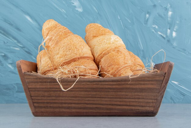 Croissants in wooden bowl on the marble background. High quality photo