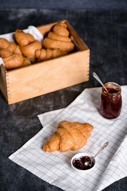  croissants in wooden box and pot with jam aside on grey table