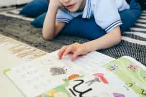 Free photo crop boy reading textbook on floor