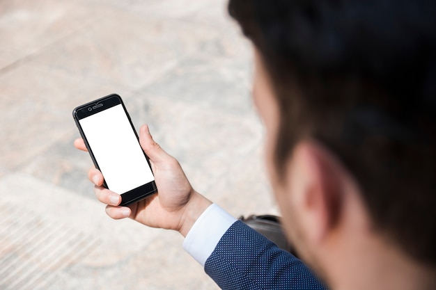 Crop businessman holding smartphone on street