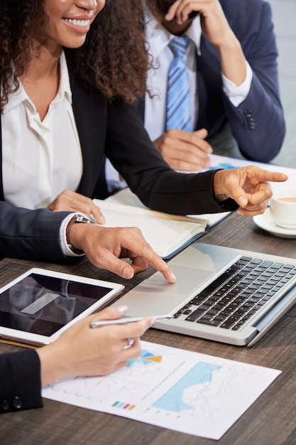 Crop businesspeople using laptop