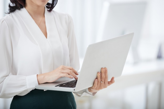 Crop businesswoman using laptop