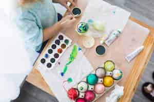 Free photo crop child painting eggs on table