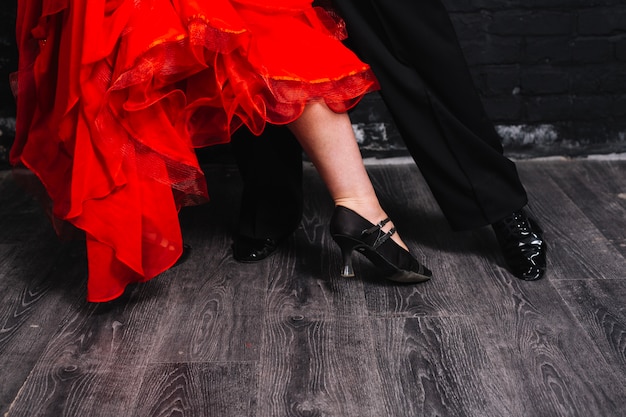 Crop couple dancing on gray parquet