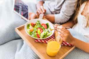 Free photo crop couple enjoying salad while watching tv series