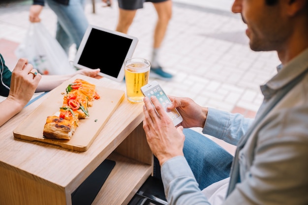 Crop couple with gadgets in street cafe