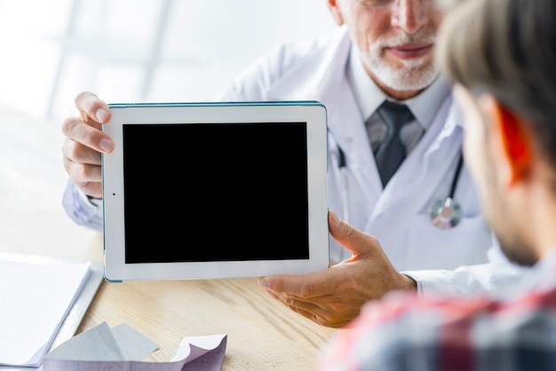 Free Photo crop doctor showing tablet to patient