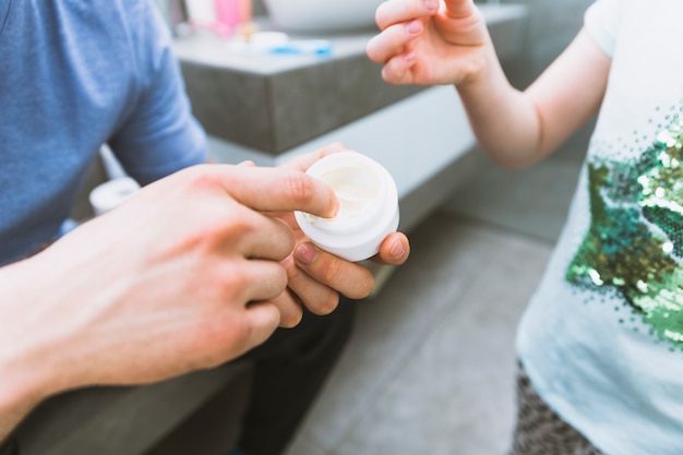 Crop father taking cream for daughter