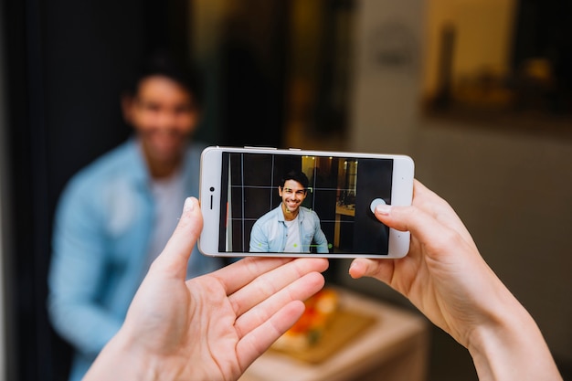 Crop female hands taking picture of man