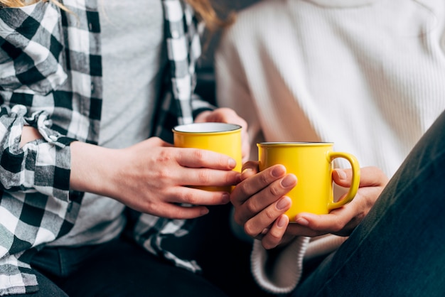 Free photo crop females holding yellow mugs