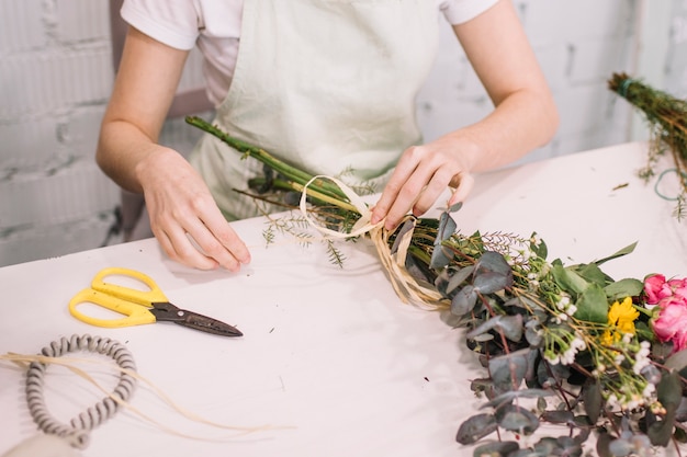 Free photo crop florist attaching ribbon to bouquet