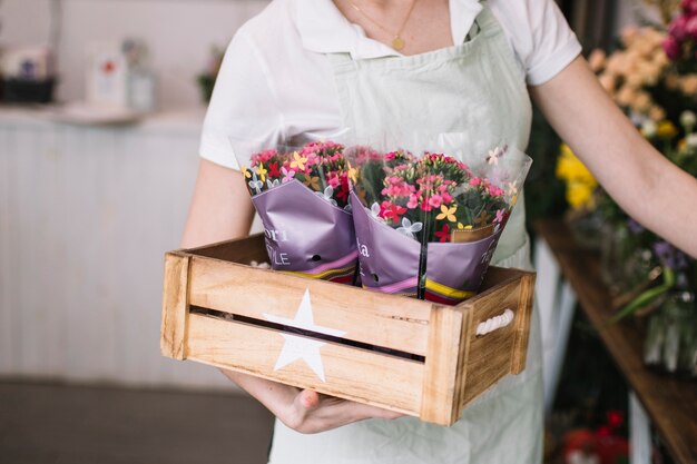 Crop florist carrying flowers in box