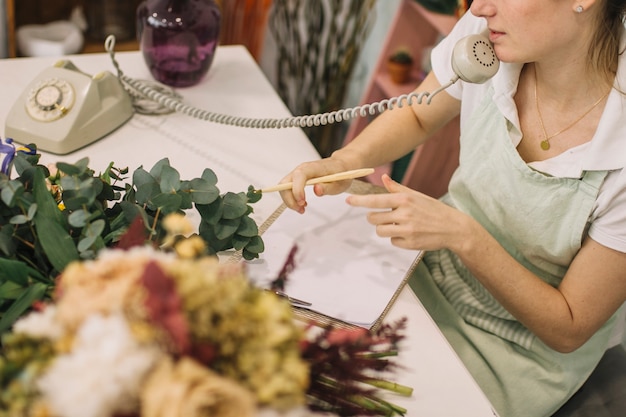 Free Photo crop florist making notes during phone conversation