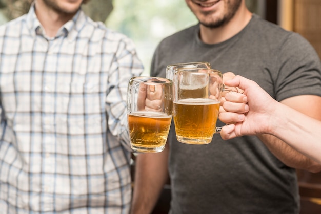 Free photo crop friends clinking mugs in bar