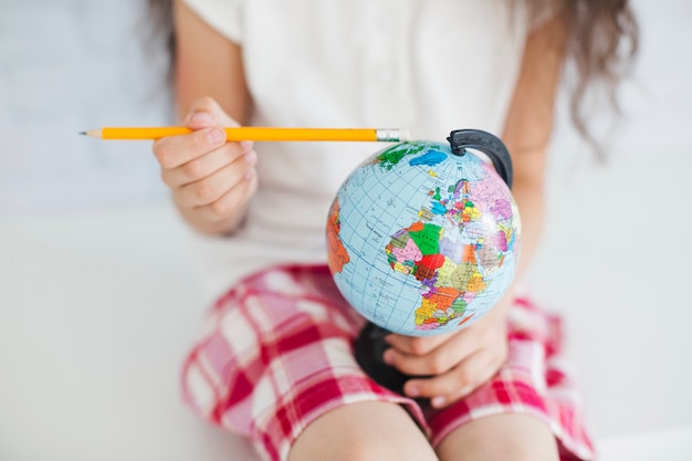 Crop girl with pencil and globe