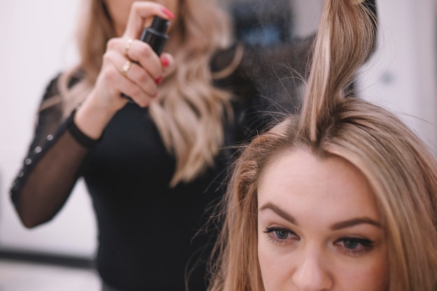 Free photo crop hairdresser applying spray on hair