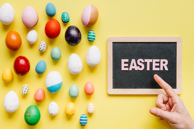 Free photo crop hand above blackboard and easter eggs