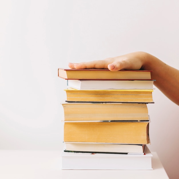 Crop hand on book pile