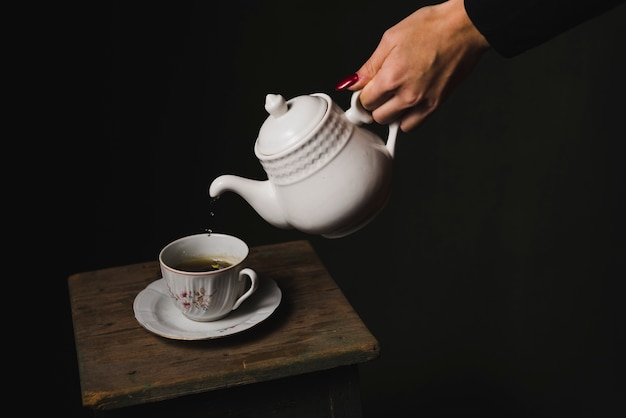 Crop hand filling cup with tea