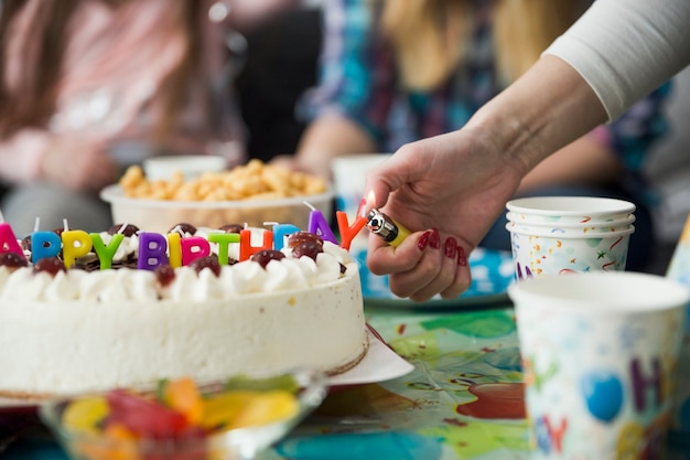 Crop hand lighting candles on birthday cake