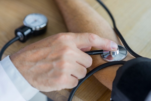 Free photo crop hand measuring blood pressure of patient