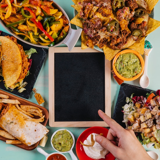 Crop hand pointing at blackboard near dishes