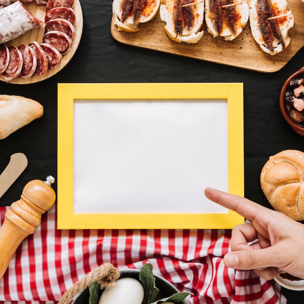 Crop hand pointing at empty frame amidst food